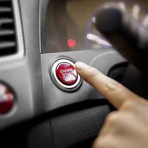 Closeup - finger pressing car engine start button.
