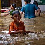 Indonesian children wade through flood waters on a street in Jakarta.