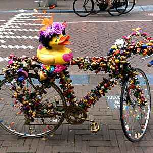 Section view of a bicycle decorated with garlands of plastic ducks and a yellow duck on the saddle on a street in Amsterdam, Holland