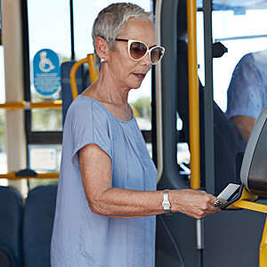 Mature woman using travel card to pay for public bus ride.