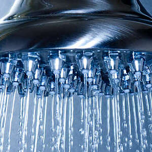 Close shot of a large shower head with multiple jets spraying water.