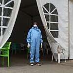 Doctor in blue overalls, gloves and mask stands at the entrance of a tent health centre in Djibouti