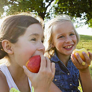 Laughing girls eating apples outdoors